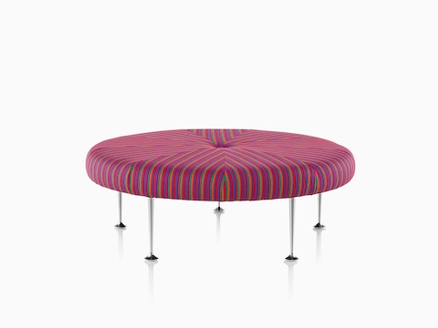 A round Girard Color Wheel Ottoman upholstered in narrow stripes of orange, green, magenta, and purple.