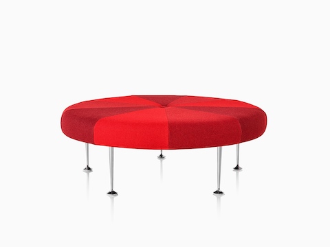A round Girard Color Wheel Ottoman upholstered in three shades of red.