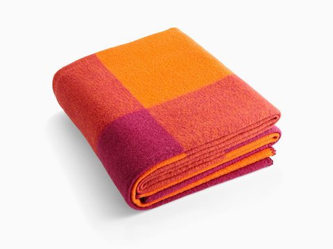 オレンジとマゼンタの色合いで折り畳まれたGirard Throw毛布。