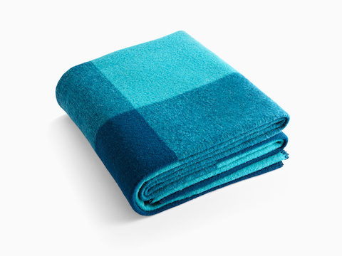 A folded Girard Throw blanket in shades of blue.