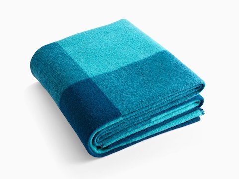 A folded Girard Throw blanket in shades of blue. A folded Girard Throw blanket in shades of blue.