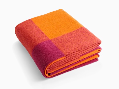A folded Girard Throw blanket in shades of orange and magenta. A folded Girard Throw blanket in shades of orange and magenta.