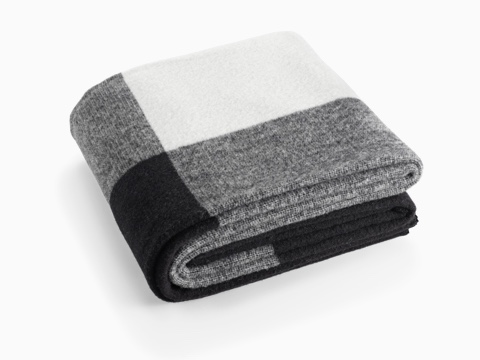 A folded Girard Throw blanket in shades of white, gray, and black. A folded Girard Throw blanket in shades of white, gray, and black.
