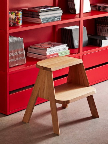 A Butler Step stool next to a red shelf.