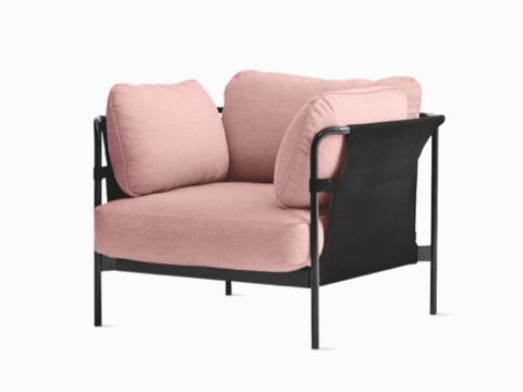 A Can Lounge Chair from HAY in pink fabric upholstery and a black frame, viewed from the front at a slight angle. A Can Lounge Chair from HAY in pink fabric upholstery and a black frame, viewed from the front at a slight angle.