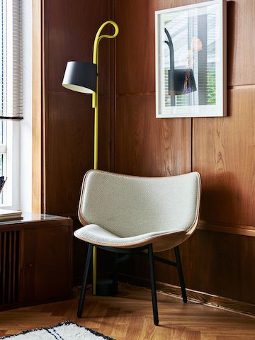 Uma Lounge Chair Dapper cinza com pernas pretas em uma sala com painéis em madeira.