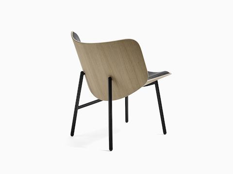 Una silla lounge Dapper en negro, vista desde atrás en ángulo para mostrar su respaldo de madera a la vista.