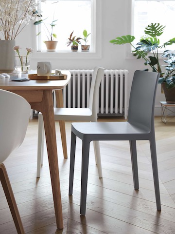 Two Élémentaire Side Chairs in cream white and blue-grey next to a dining table.