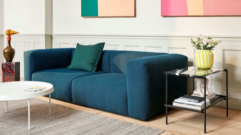 A navy blue Mags Soft Sectional Sofa with a black Rebar Side Table and Tulou Coffee Table.