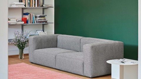 Grey, 2-piece Mags Sectional Sofa with white, round Slit Table in a living room.