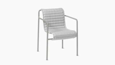 Three quarter view of a Palissade Dining Armchair Quilted Cushion in light grey.