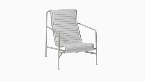 A three quarter view of a Palissade Lounge Chair High Quilted Cushion in light grey.
