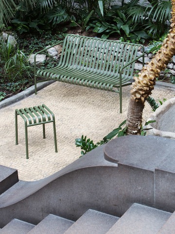 A Palissade Stool in a courtyard next to a Palissade Lounge Sofa.