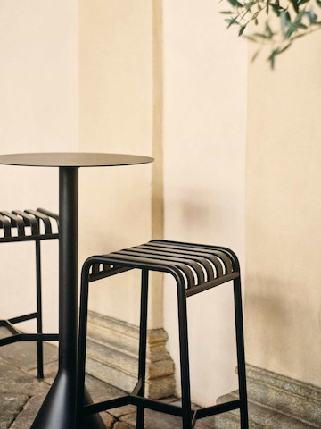 Two Palissade Stools in dark grey beside a Bistro table.