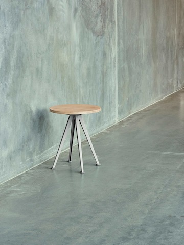Pyramid Coffee Table with oak top against a cement wall.
