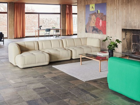 A square Kofi Coffee Table positioned next to a tan Quilton Sectional Sofa and an emerald Quilton Sofa.