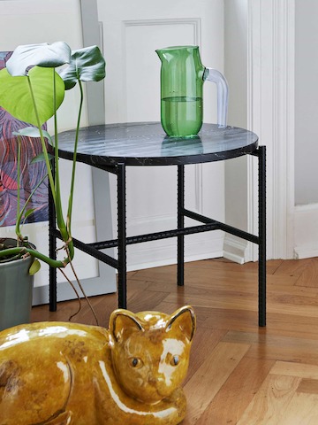 A round Rebar Side Table with green water vase on top.