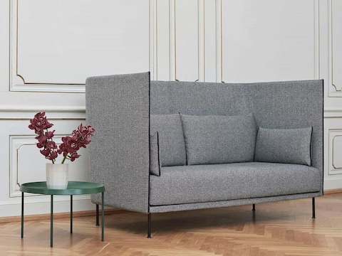 A gray high-back Silhouette Sofa next to a Tulou Coffee Table.