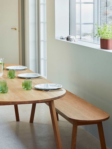 A wood Triangle Leg Table with a Triangle Leg Bench, set for a meal.