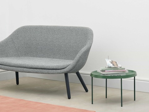 A grey About A Lounge Sofa next to a green Tulou table.