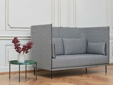 A grey high back Silhouette Sofa next to a Tulou table.