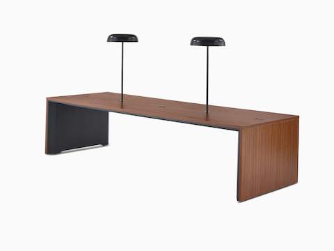 A wide, seated-height Headway Communal Table with a medium wood top and two black Ode lamps mounted on it, viewed at a 45-degree angle.