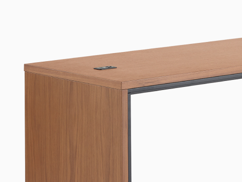 A narrow, counter-height Headway Communal Table with a medium wood top and black base viewed at a 45-degree angle.
