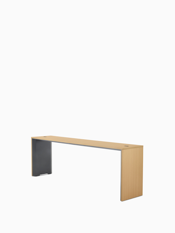 A narrow, standing-height Headway Communal Table with a light wood top and dark gray base viewed at a 45-degree angle.