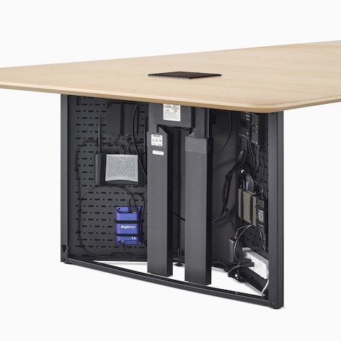 A close-up view of a Headway conference table's open cabinet base filled with technology components.