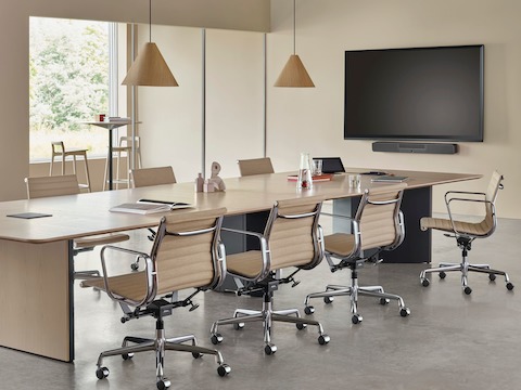 Un esquema de oficina que presenta una mesa de conferencias Headway con una base de gabinete rodeada por sillas Eames Aluminum Group.