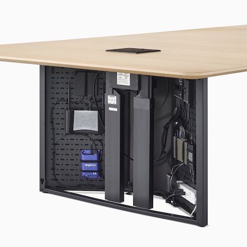 A close-up view of a Headway conference table's open cabinet base filled with technology components.