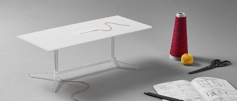 Un modelo en miniatura impreso en 3D de una mesa de conferencias Headway con tijeras y un carrete de hilo junto a ella.
