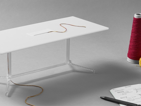 Un modelo en miniatura impreso en 3D de una mesa de conferencias Headway con tijeras y un carrete de hilo junto a ella.