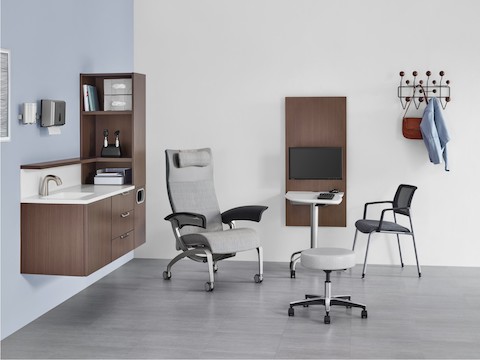 An exam room with Mora System casework in a dark brown finish and an Intent Solution table between a patient chair and side chair. An exam room with Mora System casework in a dark brown finish and an Intent Solution table between a patient chair and side chair.