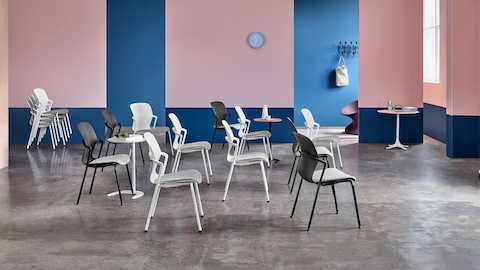 広いミーティングスペースに置かれた数脚のKeynサイドチェア（ブラックとホワイト）と、その横に積み重ねられたチェア。