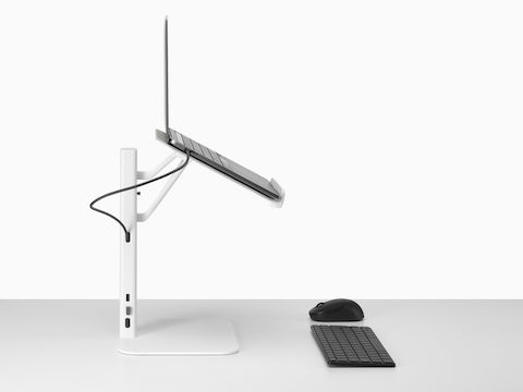 从侧面看，白色 Lana 笔记本电脑支架上装有笔记本电脑、键盘和鼠标。