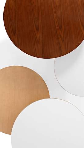 Overhead view of four round tabletops in various finishes. Select to go to the Herman Miller tables landing page.