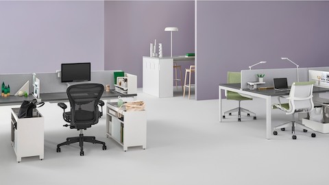 Individual Layout Studio workstations individuais com Black Aeron Chairs e cadeiras estofadas em verde Setu, com itens pessoais e iluminação de tarefa.