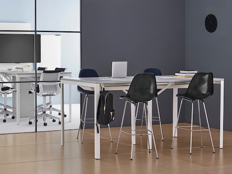 Black Eames molded fiberglass stools with navy blue upholstery at a Layout Studio standing-height table.