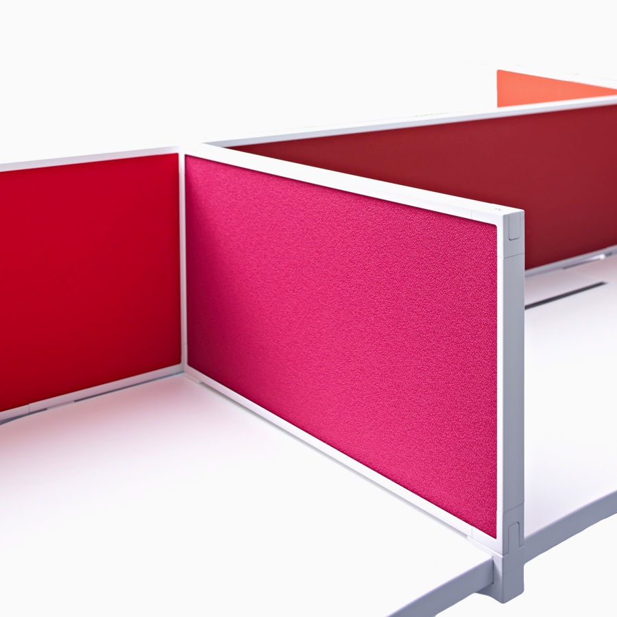 Close-up of the framed red fabric, delineation privacy screen that's placed on top of a work surface to divide desk space.