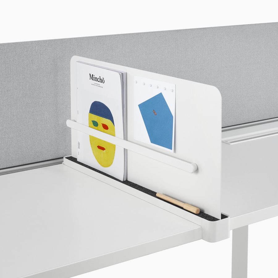Close-up of a white Ubi Slim Screen, installed on a Layout Studio work surface, that's holding a magazine and marker. Close-up of a white Ubi Slim Screen, installed on a Layout Studio work surface, that's holding a magazine and marker.