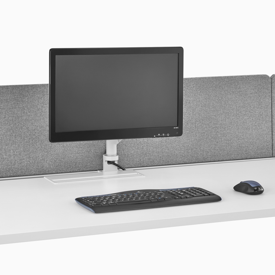 Close-up of a Layout Studio workstation with a white top, gray flat edge fabric, center privacy screen, a monitor, keyboard, and mouse on the surface.