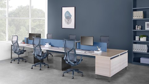 Mobilier système de bureau Layout Studio pour six personnes avec un écran de séparation bleu, une crédence, des sièges Cosm bleu foncé et un caisson de rangement.