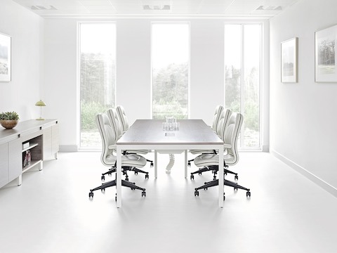 Natural light flows through a conference room equipped with a Layout Studio table, credenza, and white leather chairs.