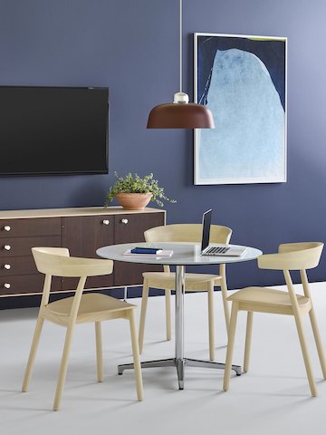 Uma área para reuniões íntima com três cadeiras Leeway com acabamento em madeira clara ao redor de uma mesa com tampo de vidro Saiba com base polida.