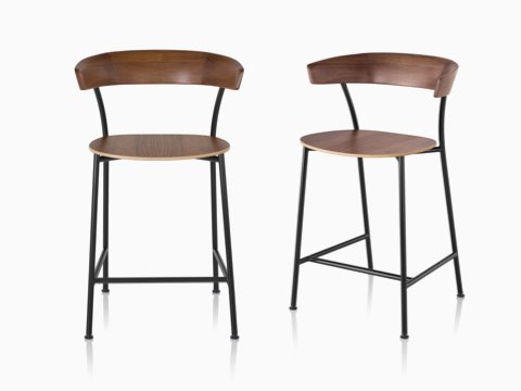 Two Leeway Stools with black metal bases and dark brown wood seats and backrests, one viewed from the front, the other viewed from an angle.