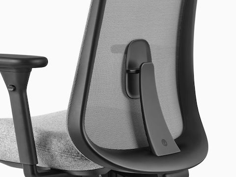 Feche acima da imagem de uma cadeira Lino preta e cinzenta com apoio lombar sacral ajustável, visto da parte traseira em um ângulo.