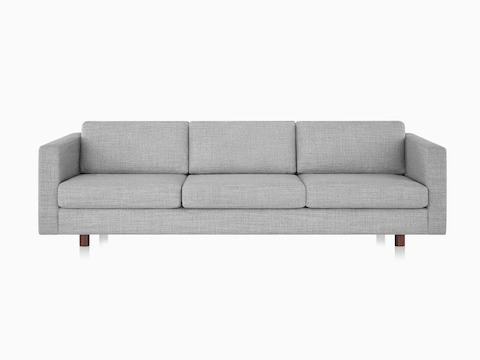 Ein Lispenard Sofa mit grauem Textilbezug und Nussbaum-Beinen, im niedrigen Winkel von vorne betrachtet.