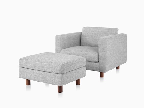 Ein Lispenard Lounge-Sessel und Ottoman mit grauem Textilbezug und Nussbaum-Beinen, im schrägen Winkel betrachtet.