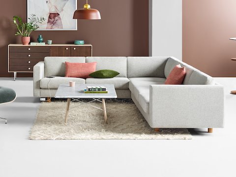Lounge de escritório com sofá Lispenard seccional cinza com pés em carvalho acompanhado de Eames Lounge e Otomana em tecido cinza.